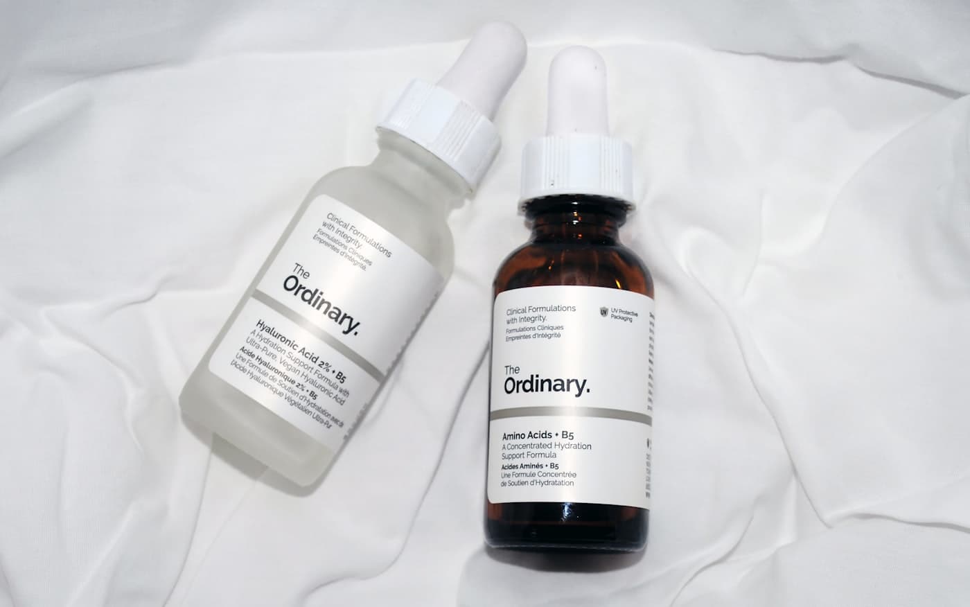 Two treatment serums on soft white linen
